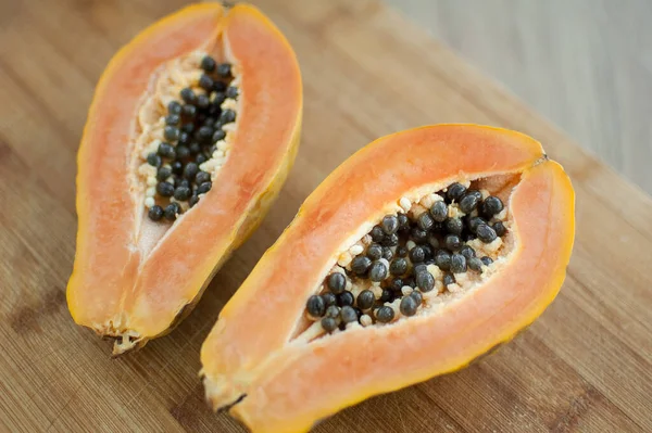 Fresh organic ripe papaya fruit cut in half on a wooden board. Exotic fruits, healthy eating concept — Stock Photo, Image