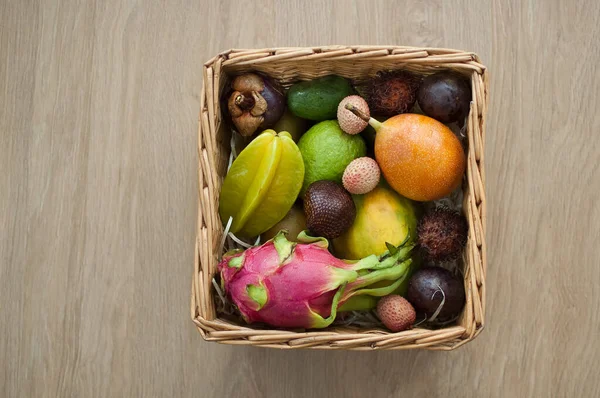 Großer Korb mit frischen tropischen Früchten, Passionsfrüchten, Karambolen, Drachenfrüchten oder Pitaya, Mangostan, Lichi, Granadilla. Exotische Früchte, gesundes Essen — Stockfoto