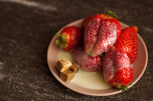 Red ripe strawberries on round plate with a few cane sugar pieces and melted white chocolate — Stock Photo, Image