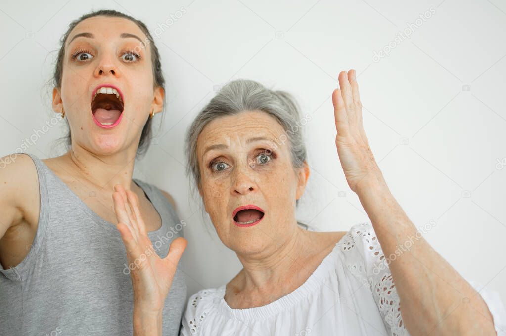 Emotional adult daughter with her senior moter are screaming and looking at the camera, crazy family of different age generations having fun on white background, mothers day