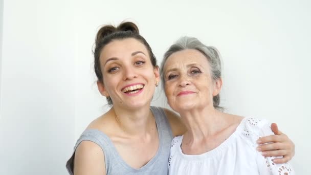 Feliz madre mayor está abrazando a su hija adulta, las mujeres se ríen juntas, familia sincera de diferentes generaciones de edad que se divierten en el fondo blanco — Vídeos de Stock
