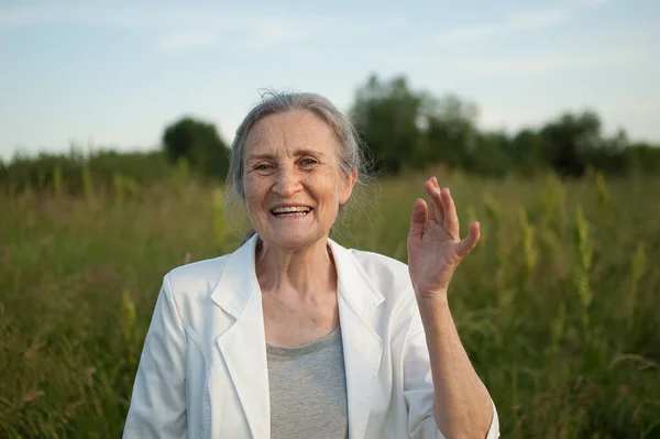 Retrato de mujer mayor con el pelo gris y la cara con arrugas con chaqueta blanca y relajarse en el parque durante el día soleado —  Fotos de Stock