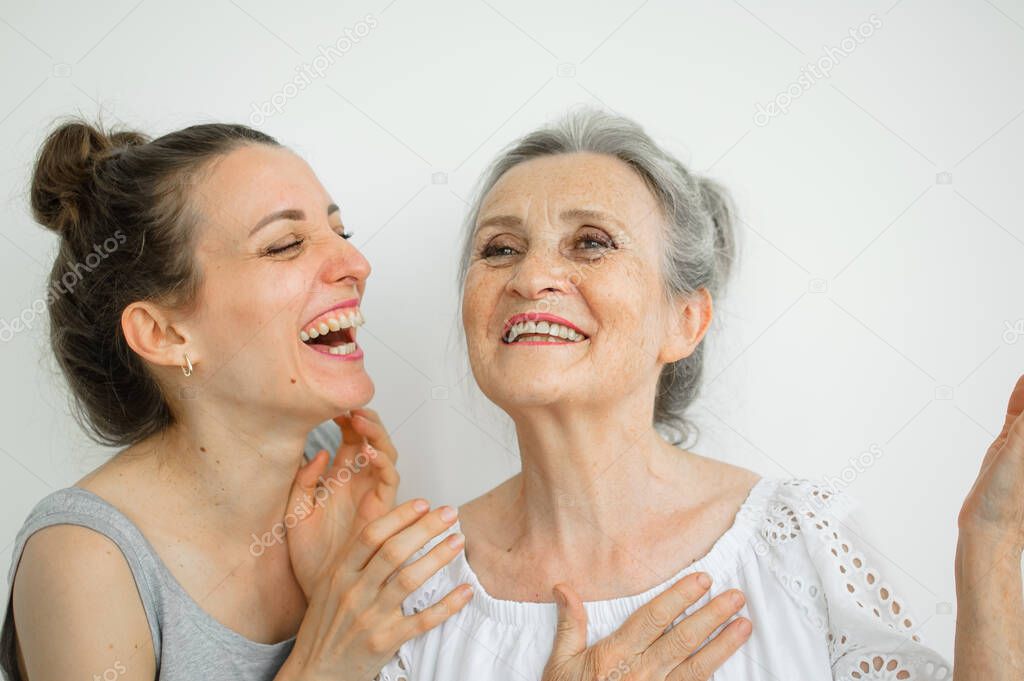 Emotional adult daughter with her senior moter are screaming and looking at the camera, crazy family of different age generations having fun on white background, mothers day