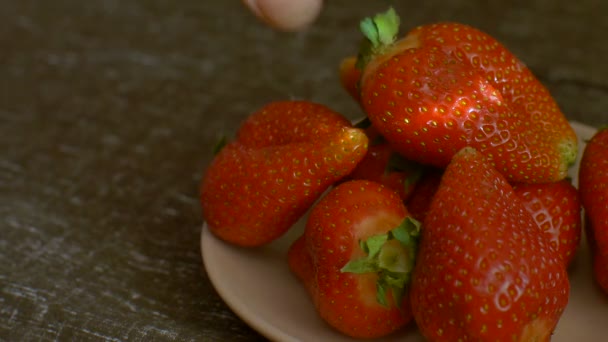 여자들은 손으로 나무 탁자 위에 깔끔하게 놓여 있는 딸기 한 개를 잡으려 한다. 건강에 좋은 식사 개념 — 비디오