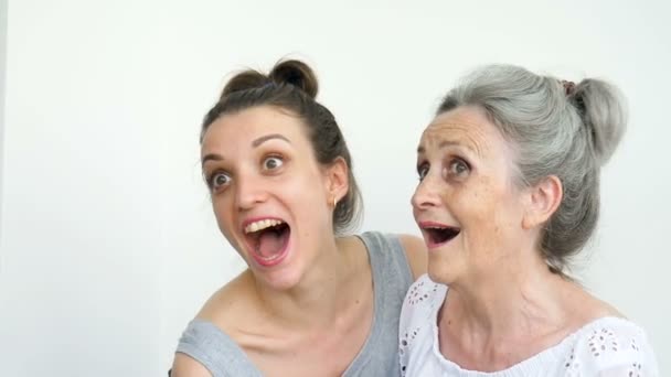 Ευτυχισμένη ηλικιωμένη μητέρα αγκαλιάζει την ενήλικη κόρη της, οι γυναίκες γελούν μαζί, ειλικρινή οικογένεια διαφορετικών ηλικιών που διασκεδάζουν σε λευκό φόντο — Αρχείο Βίντεο