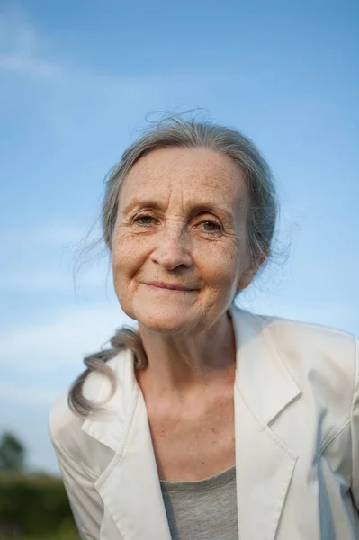 Portret van oudere vrouw met grijs haar en gezicht met rimpels in witte jas en ontspannen in het park bij zonnig weer, Moederdag — Stockfoto