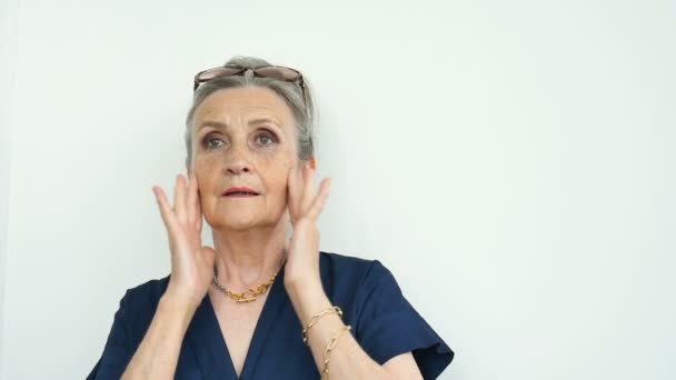 В помещении портрет встревоженной шокированной пожилой женщины в шоке с обеими руками на лице из-за страха и стресса на белом фоне, стрессовой пенсии, плохих новостей — стоковое видео