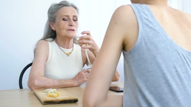 Portrait féminin de fille adulte et mère aînée parlant et buvant du champagne à la maison assise à la table, retraite heureuse, concepts de la fête des mères, dépendance à l'alcool — Video