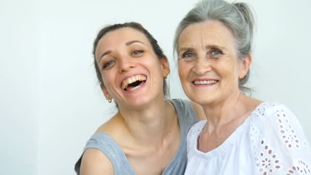 행복 한 노모가 그녀의 성인 딸을 껴안고 있습니다. 여성들은 함께 웃고 있습니다. 서로 다른 세대의 진실 한 가족들이 하얀 배경에서 재미를 보고 있습니다. — 비디오