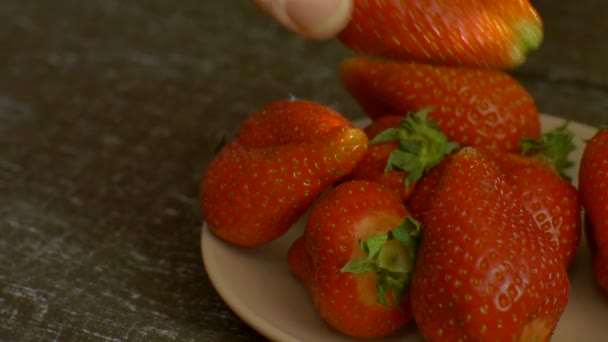 Kvinnors hand är att sätta jordgubben till vit tallrik på träbord. Hälsosam kost, kost koncept — Stockvideo