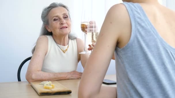 Portret dorosłej córki i starszej matki rozmawiającej i pijącej szampana w domu, siedzącej przy stole, szczęśliwa emerytura, koncepcje Dnia Matki, uzależnienie od alkoholu — Wideo stockowe