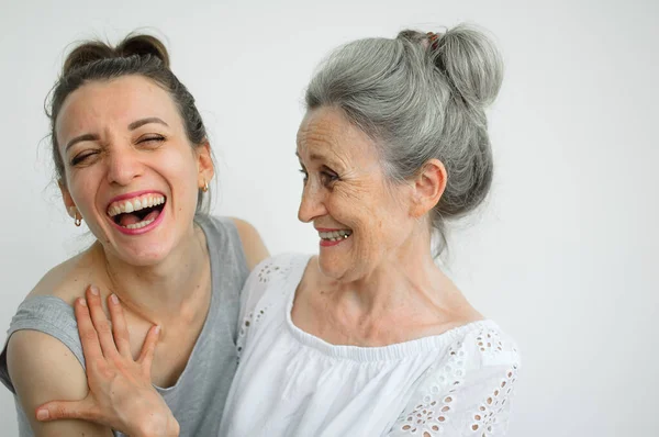 Feliz madre mayor está abrazando a su hija adulta, las mujeres se ríen juntas, familia sincera de diferentes generaciones de edad que se divierten en el fondo blanco, día de las madres. —  Fotos de Stock