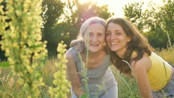 Ältere Mutter mit grauen Haaren mit ihrer erwachsenen Tochter, die im Garten in die Kamera schaut und sich an sonnigen Tagen im Freien umarmt, Muttertag — Stockvideo