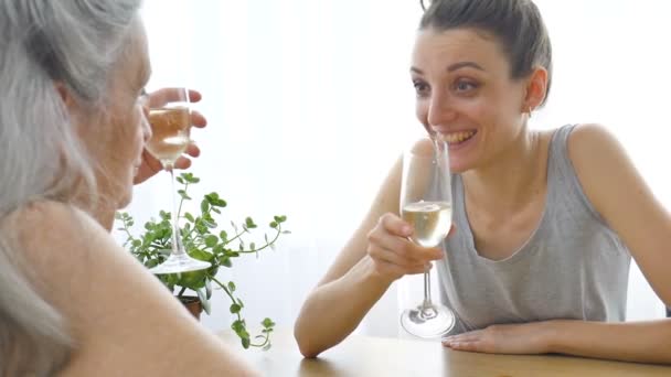 Retrato feminino de filha adulta e mãe idosa conversando e bebendo champanhe em casa sentada à mesa, aposentadoria feliz, conceitos do dia das mães, dependência de álcool — Vídeo de Stock