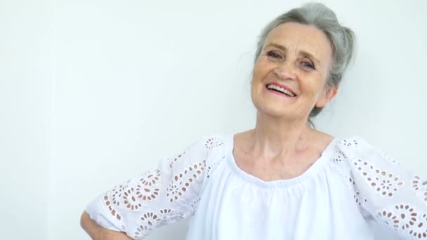 Vacker gammal mormor med grått hår och ansikte med rynkor tittar på kameran med leende på vit bakgrund, mödrar dag, glad pension — Stockvideo