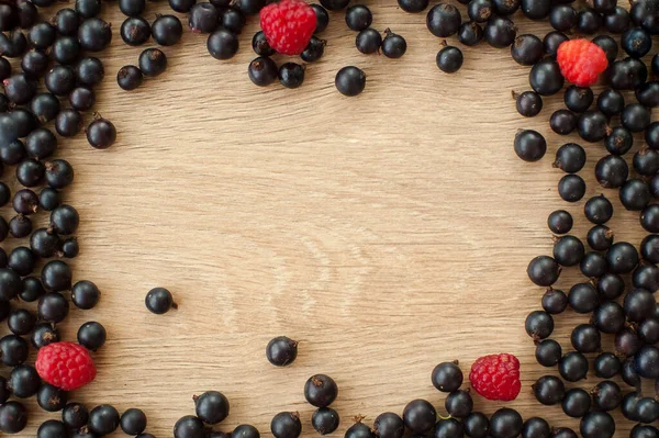 Свіжі органічні ягоди, чорна смородина і малина, на дерев'яному столі. Сира їжа та здорове харчування, ягідна дієта. Складові для коктейлів. Рамка, простір для копіювання напис — стокове фото