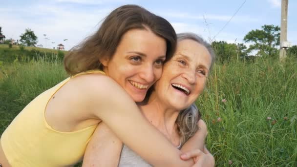 Ibu senior dengan rambut abu-abu dengan putri dewasanya di taman saling berpelukan selama piknik di siang hari yang cerah, ibu-ibu berpelukan — Stok Video