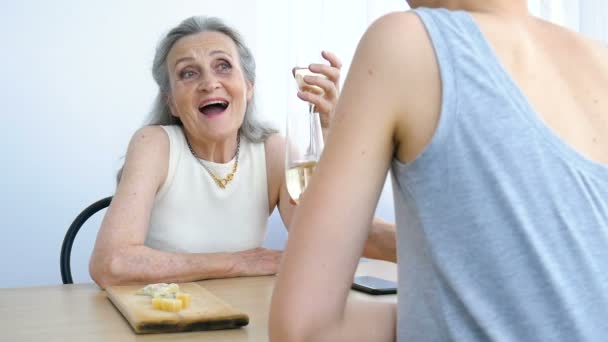 Portret dorosłej córki i starszej matki rozmawiającej i pijącej szampana w domu, siedzącej przy stole, szczęśliwa emerytura, koncepcje Dnia Matki, uzależnienie od alkoholu — Wideo stockowe