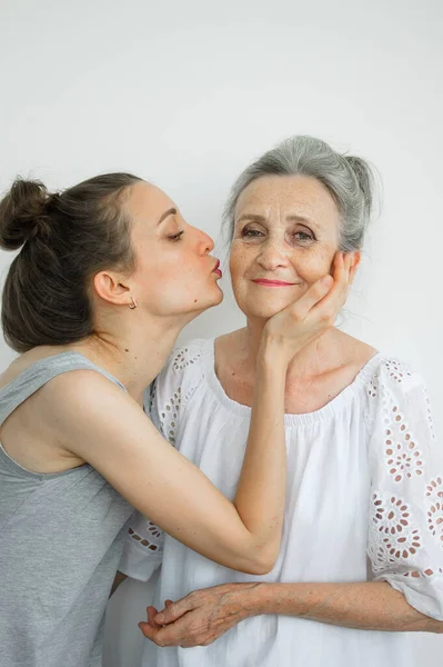 Feliz madre mayor está abrazando a su hija adulta, las mujeres se ríen juntas, familia sincera de diferentes generaciones de edad que se divierten en el fondo blanco, día de las madres. —  Fotos de Stock