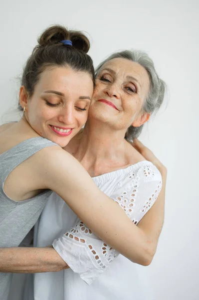 Feliz madre mayor está abrazando a su hija adulta, las mujeres se ríen juntas, familia sincera de diferentes generaciones de edad que se divierten en el fondo blanco, día de las madres. —  Fotos de Stock