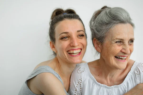 Feliz madre mayor está abrazando a su hija adulta, las mujeres se ríen juntas, familia sincera de diferentes generaciones de edad que se divierten en el fondo blanco, día de las madres. —  Fotos de Stock
