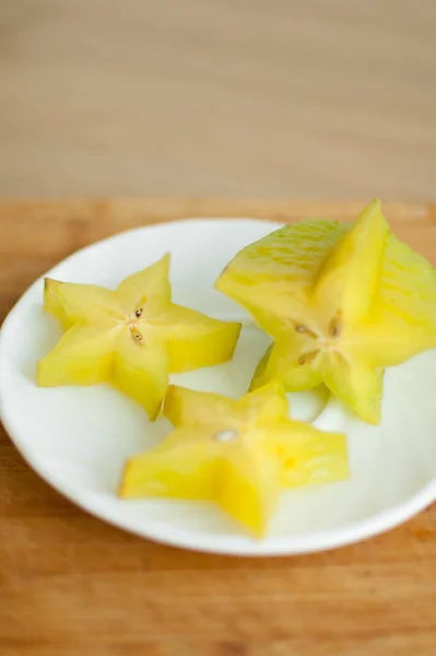 Egzotyczne starfruit lub averrhoa carambola na białym talerzu na drewnianej desce cięcia. Zdrowe jedzenie, świeże organiczne owoce jabłka. — Zdjęcie stockowe