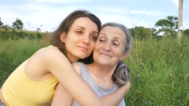 Madre anziana con i capelli grigi con la figlia adulta in giardino che si abbraccia durante il picnic durante la giornata di sole all'aperto, la giornata delle madri — Video Stock