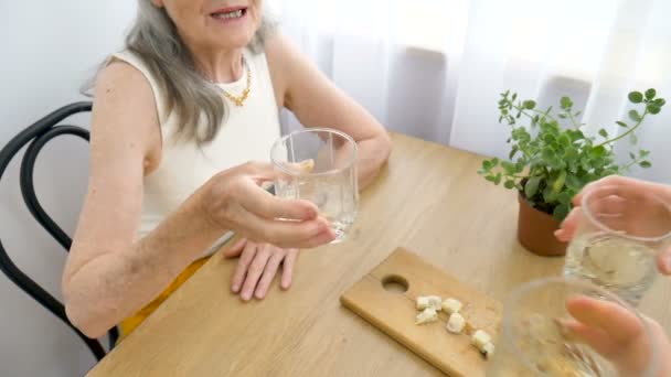 Portrait féminin de la mère aînée parlant et buvant de l'alcool et des lunettes à la maison assise à la table, retraite heureuse, concepts de la fête des mères, dépendance à l'alcool — Video