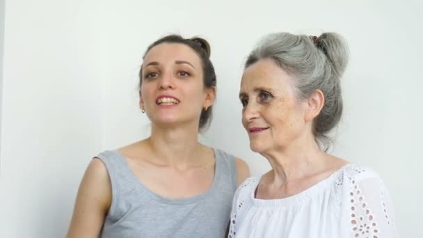 Szczęśliwa starsza matka przytula swoją dorosłą córkę, kobiety śmieją się razem, szczera rodzina w różnym wieku bawi się na białym tle — Wideo stockowe
