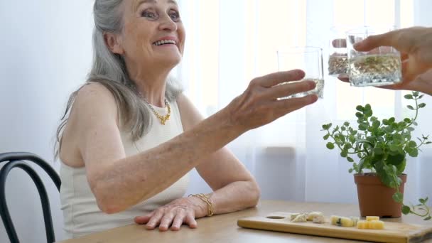 Portrait féminin de la mère aînée parlant et buvant de l'alcool et des lunettes à la maison assise à la table, retraite heureuse, concepts de la fête des mères, dépendance à l'alcool — Video