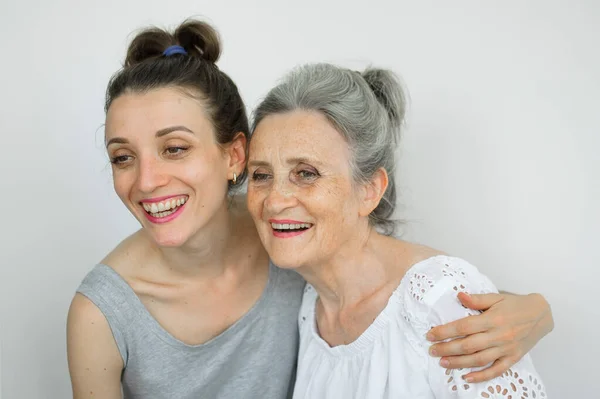 Feliz madre mayor está abrazando a su hija adulta, las mujeres se ríen juntas, familia sincera de diferentes generaciones de edad que se divierten en el fondo blanco, día de las madres. —  Fotos de Stock