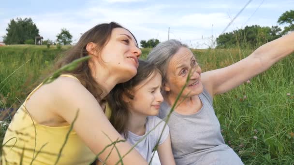 Schattig kind meisje met haar jonge moeder en senior oma hebben picknick tijdens de zomer buiten in de natuur, moeders dag, gelukkig pensioen, multi generatie familie — Stockvideo