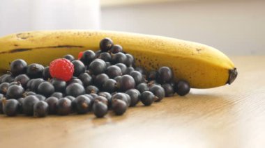 Taze organik böğürtlen, siyah frenk üzümü ahududu ve muz ahşap bir masada. Çiğ yemek, sağlıklı beslenme, böğürtlen diyeti. Smoothie için İçecekler