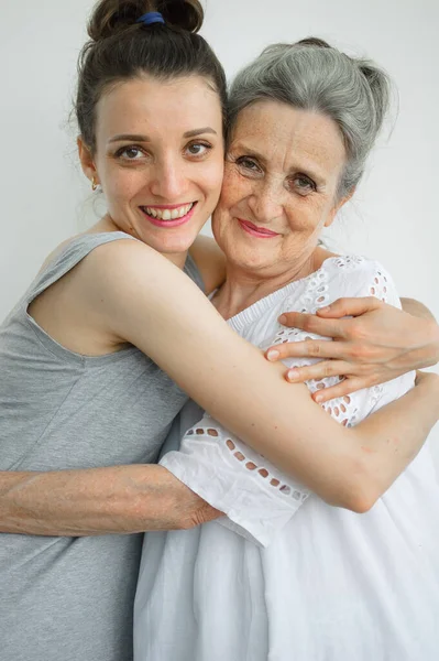 Feliz madre mayor está abrazando a su hija adulta, las mujeres se ríen juntas, familia sincera de diferentes generaciones de edad que se divierten en el fondo blanco, día de las madres. —  Fotos de Stock