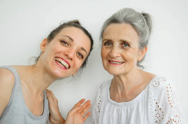 Feliz madre mayor está abrazando a su hija adulta, las mujeres se ríen juntas, familia sincera de diferentes generaciones de edad que se divierten en el fondo blanco, día de las madres. —  Fotos de Stock