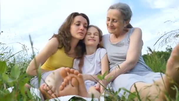 Schattig kind meisje met haar jonge moeder en senior oma hebben picknick tijdens de zomer buiten in de natuur, moeders dag, gelukkig pensioen, multi generatie familie — Stockvideo