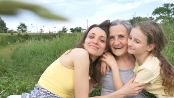 Schattig kind meisje met haar jonge moeder en senior oma hebben picknick tijdens de zomer buiten in de natuur, moeders dag, gelukkig pensioen, multi generatie familie — Stockvideo