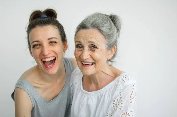 Feliz madre mayor está abrazando a su hija adulta, las mujeres se ríen juntas, familia sincera de diferentes generaciones de edad que se divierten en el fondo blanco, día de las madres. —  Fotos de Stock