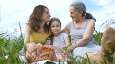 Genç annesi ve büyük annesiyle birlikte tatlı bir kız çocuğu yaz boyunca doğada piknik yapıyor anneler günü, mutlu emeklilik, çok nesilli aile.