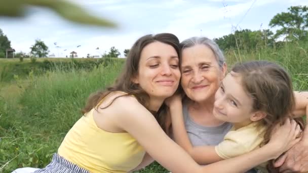 Menina bonito com sua jovem mãe e avó sênior estão tendo piquenique durante o verão ao ar livre na natureza, dia das mães, aposentadoria feliz, família de várias gerações — Vídeo de Stock