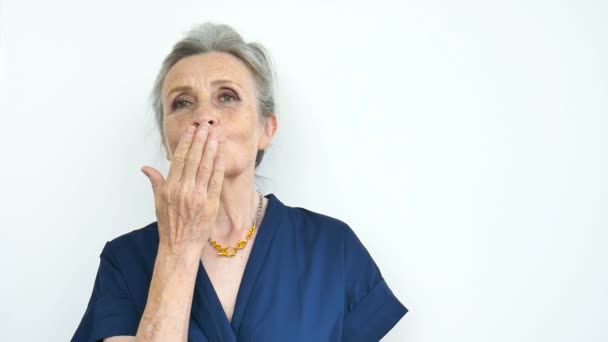 Belle vieille grand-mère drôle avec des cheveux gris et le visage avec des rides envoie baiser d'air et en regardant la caméra sur fond blanc, fête des mères, retraite heureuse — Video