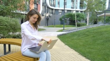 Dizüstü bilgisayarın klavyesinde yazan genç bir kadın, modern binanın arka planında dijital tablet kullanan bir iş kadını, açık havada çalışan bir hesap yöneticisi, uzak bir iş.