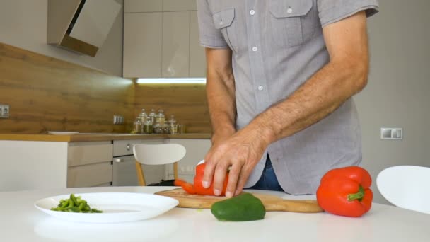 Нарезаю красный перец на деревянной доске. Мужчина режет ножом капсикум. Человек режет сладкие овощи. Концепция здорового питания, диетическое питание, приготовление пищи дома — стоковое видео