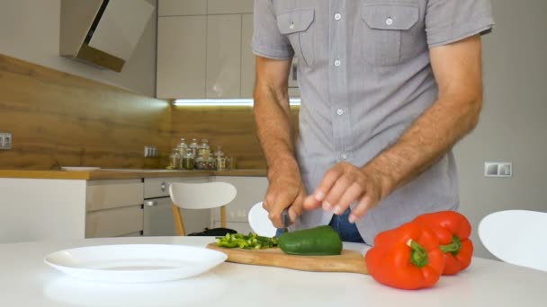 Corte de pimentão verde em tábua de corte de madeira. Mão masculina corta capsicum com faca. O homem está a cortar os vegetais doces. Conceito de alimentação saudável, alimentação alimentar, cozinhar em casa — Vídeo de Stock