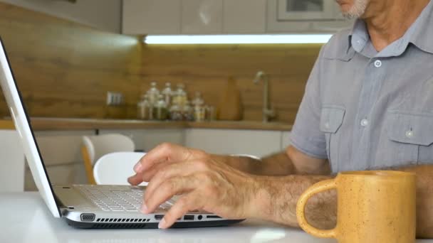 Senior homme tape sur le clavier de l'ordinateur portable, homme d'affaires utilise tablette numérique à la maison à la cuisine, gestionnaire de compte de travail, travail à distance — Video