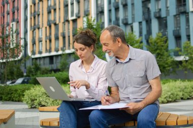 Çekici genç kadın ve son sınıf öğrencisi modern yerleşim yerlerindeki bankta otururken dizüstü bilgisayar kullanıyorlar. Ofis dışında sıradan bir toplantı. Bir kız babası için teknoloji dersi veriyor.