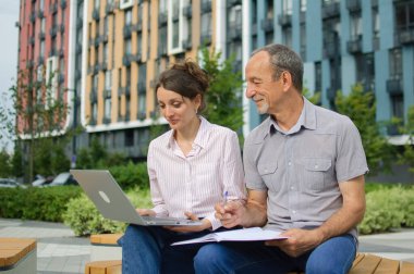 Çekici genç kadın ve son sınıf öğrencisi modern yerleşim yerlerindeki bankta otururken dizüstü bilgisayar kullanıyorlar. Ofis dışında sıradan bir toplantı. Bir kız babası için teknoloji dersi veriyor.
