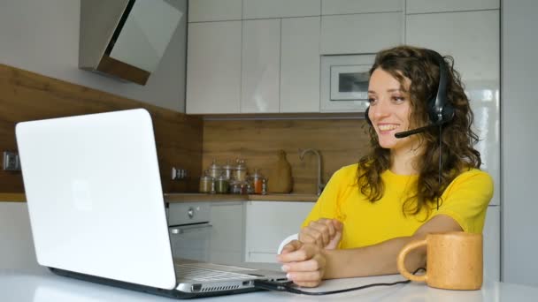 Молодая женщина проводит онлайн-встречу с помощью ноутбука, деловая женщина с цифровым планшетом сидит на кухне в своей квартире, менеджер по работе с клиентами, работает на открытом воздухе, удаленная работа, поддержка — стоковое видео