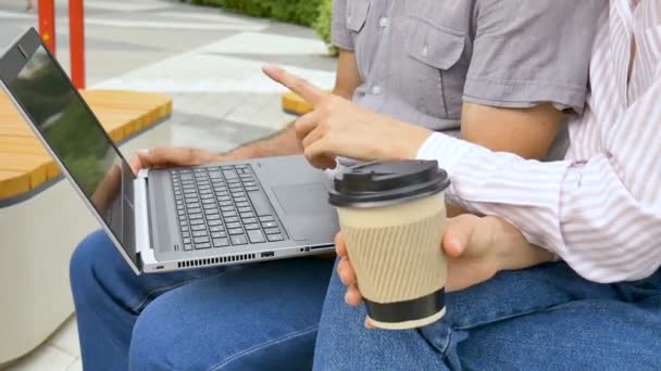 这位年轻的员工正在教她的老同事如何在办公室外的长椅上使用笔记本电脑和公司软件，如何与同事互相配合，如何与同事建立教育伙伴关系. — 图库视频影像