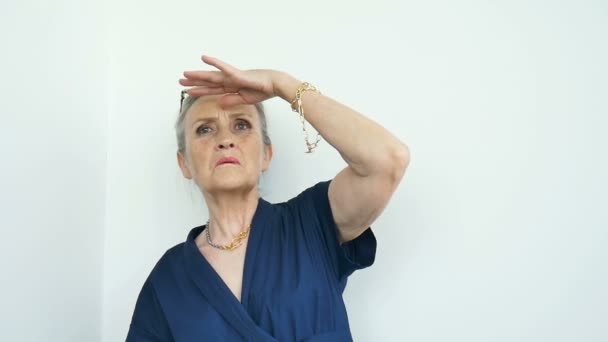 Portrait féminin de belle vieille grand-mère aux cheveux gris et le visage avec des rides est grimaçant tout en regardant la caméra sur fond blanc, fête des mères, retraite heureuse — Video